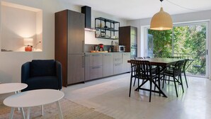 Een moderne keuken met een eethoek, met een groot raam en uitzicht op groen.