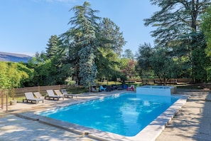 A rectangular swimming pool with lounge chairs and a wooden deck.
