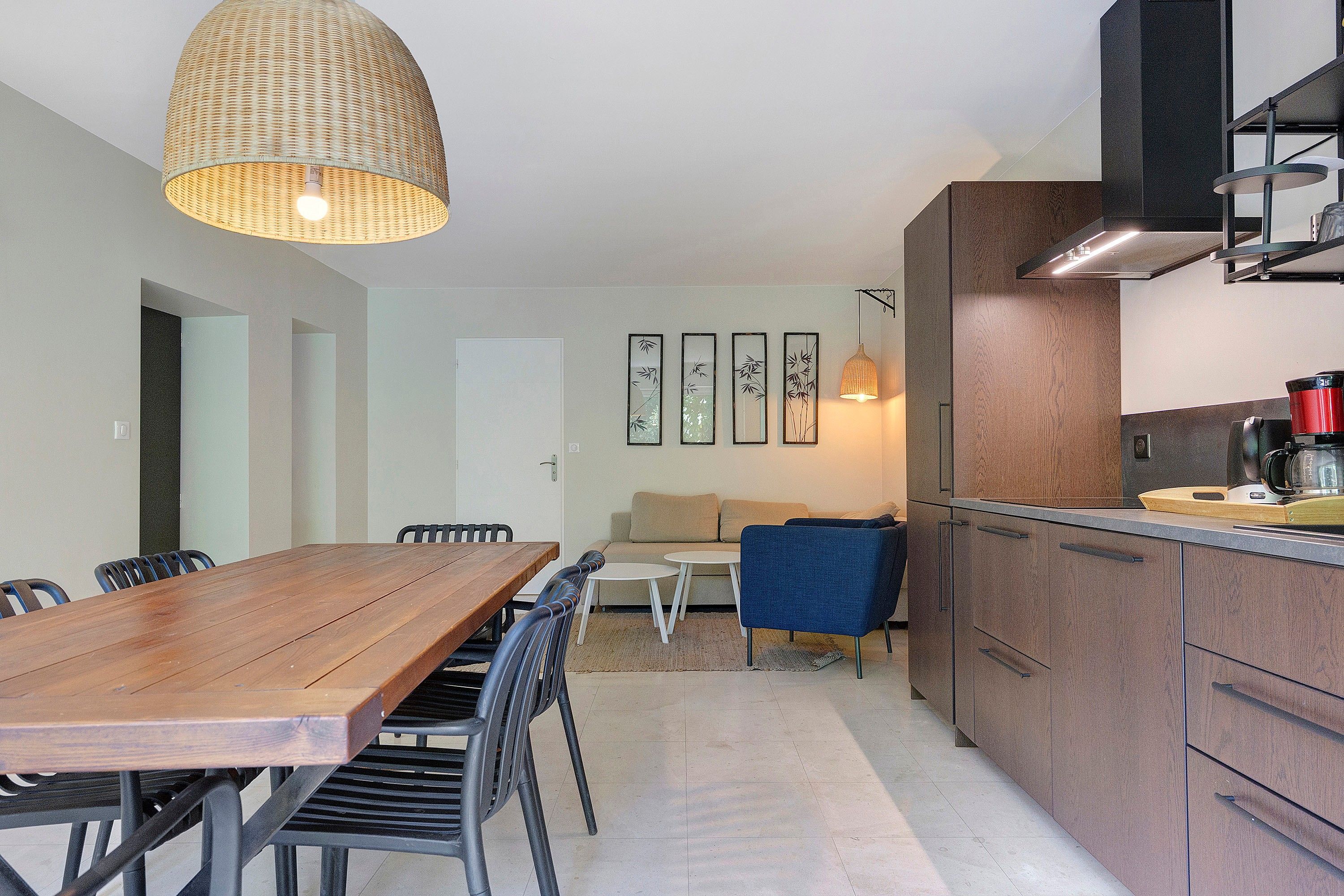 A modern kitchen with wooden cabinets, a dining table with chairs, and a sofa.