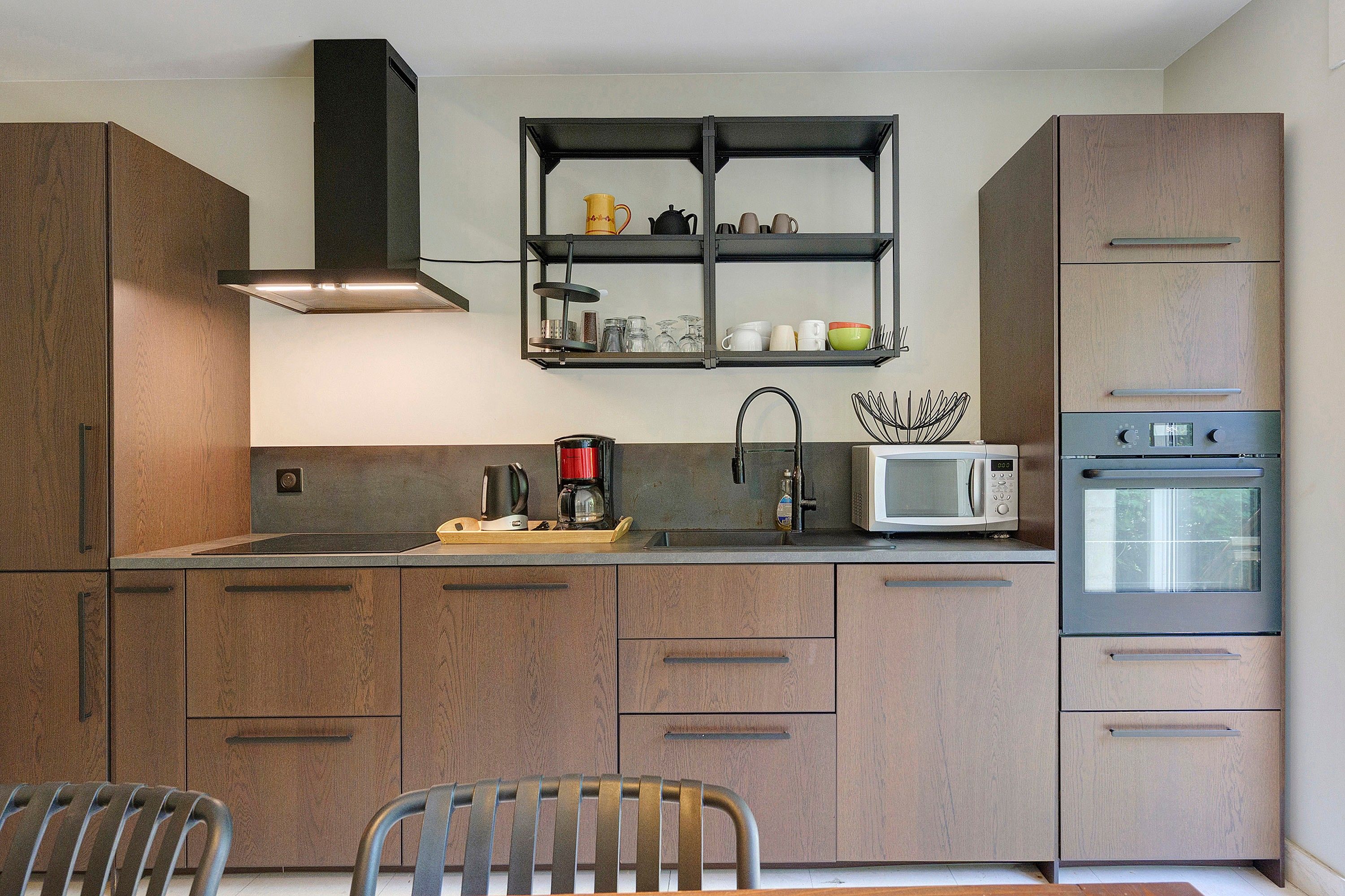 Een moderne keuken met houten kastjes, een roestvrijstalen afzuigkap, een magnetron en een oven.