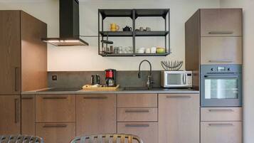 Een moderne keuken met houten kastjes, een roestvrijstalen afzuigkap, een magnetron en een oven.