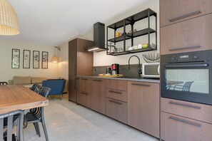 A modern kitchen with wooden cabinets, a built-in oven, and a dining area with a table and chairs.
