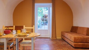 A dining area with a table set for four, a sofa, and a door leading outside.