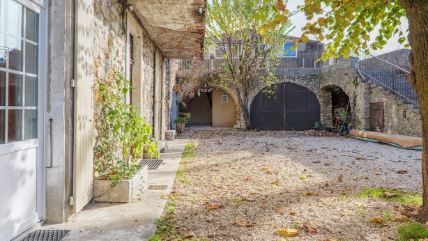 A courtyard with stone walls, a tree, and a building entrance.