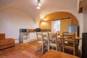 Una cocina compacta con comedor, microondas, refrigerador y piso de baldosas.