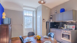 A modern kitchen with a dining area, a microwave, a coffee maker, and a bowl of fruit on the table. - Gîte Yves Apartment with Park View, Private Pool, and Wi-Fi (Vallon-Pont-d'Arc)