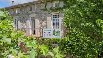 A stone building with shutters, a balcony, and a sign advertising 'Gites Le Parc'.