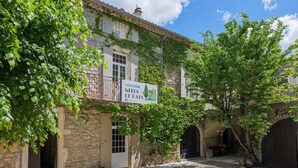 Un bâtiment en pierre avec une enseigne indiquant « Gîtes Le Parc » et un arbre devant.