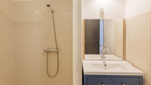 Une salle de bain avec une douche, un lavabo et un miroir.