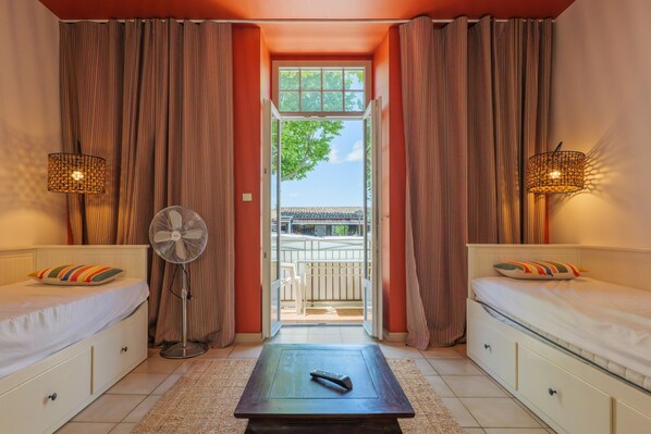 Una habitación con dos camas, un ventilador, un control remoto y vistas por una ventana.
