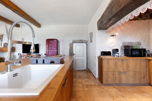 Een keuken met een houten aanrecht, een rode apparatuur en een witte deur.
