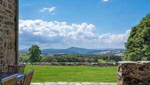 Un patio de piedra con vistas a un campo verde y montañas lejanas.