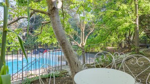 A poolside area with metal chairs and a table, surrounded by trees and a fence. - Robert Delaunay Gîte with Wi-Fi in Vallon-Pont-d'Arc (Vallon-Pont-d'Arc)