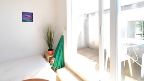 A room with a bed, a window, a small table, a potted plant, and a wall-mounted picture. - Robert Delaunay Gîte with Wi-Fi in Vallon-Pont-d'Arc (Vallon-Pont-d'Arc)