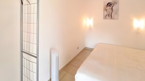 Une chambre avec un lit, un espace douche doté d’une porte en verre et un luminaire fixé au mur.