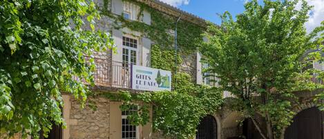 Edificio de piedra con un cartel que dice 'Gites Le Parc' y un árbol frente a él.