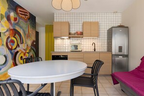 Une cuisine compacte comprenant un coin repas, un réfrigérateur et un four à micro-ondes.
