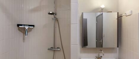 A bathroom with a shower, sink, and mirror.