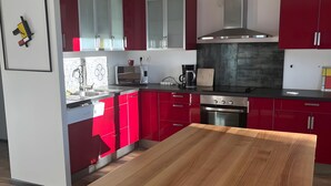 Eine moderne Küche mit roten Schränken, einem Holztisch und einer Edelstahl-Dunstabzugshaube.