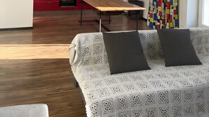 Ein modernes Wohnzimmer mit einer Couch, einem Couchtisch und einer Küche im Hintergrund.