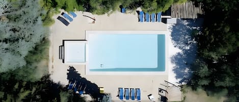 Ein Luftbild eines Schwimmbeckens mit Liegestühlen und einer Holzterrasse.