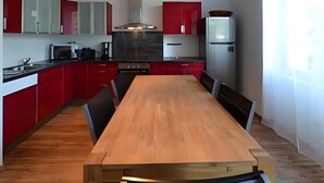 Eine moderne Küche mit roten Schränken, einem Holzespeisetisch und einem eingebauten Backofen.
