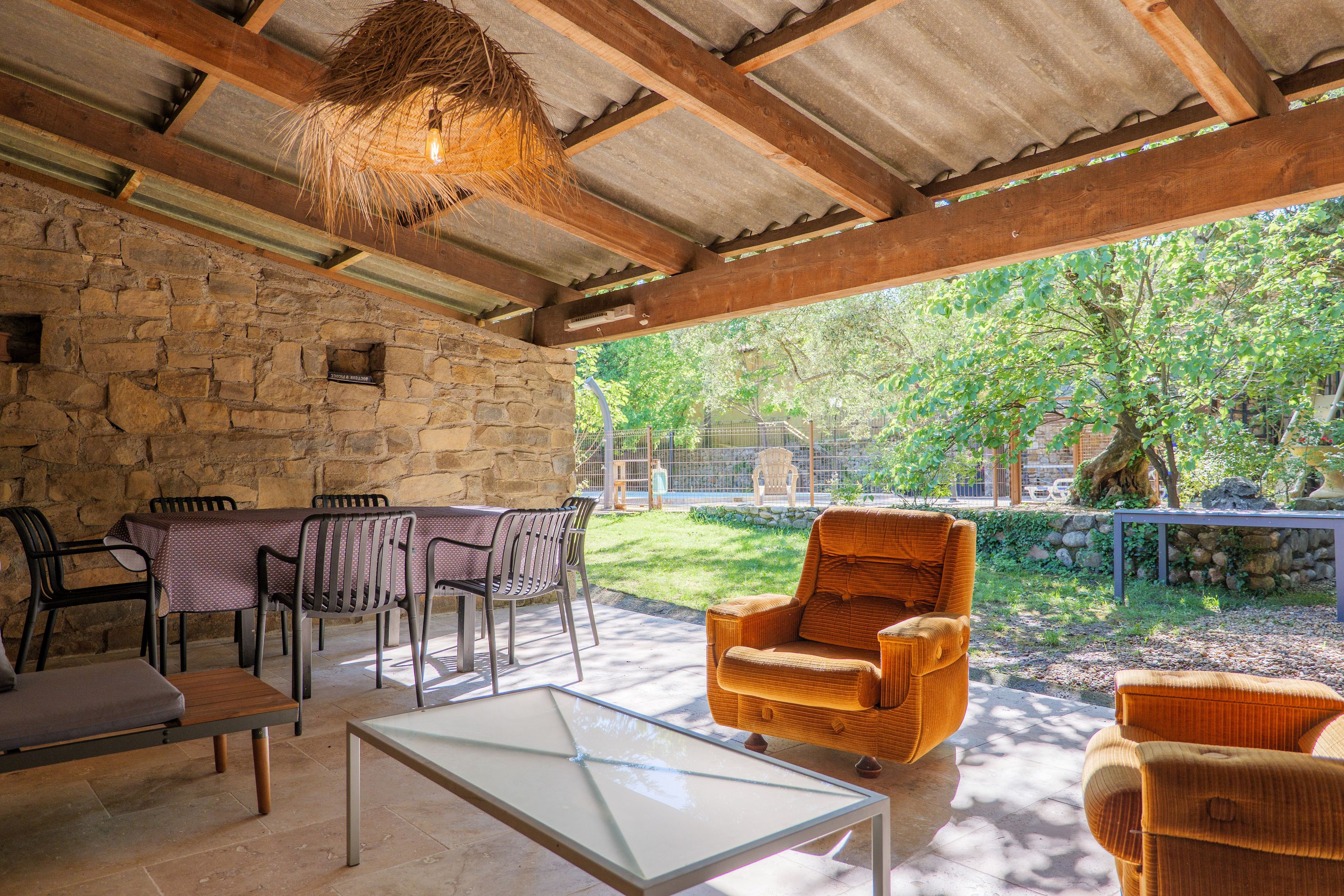 Patio esterno con pareti in pietra, un tavolo con sedie e un lampadario.