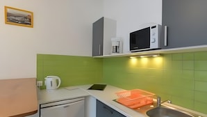 Una cocina compacta con microondas, cafetera y lavabo.