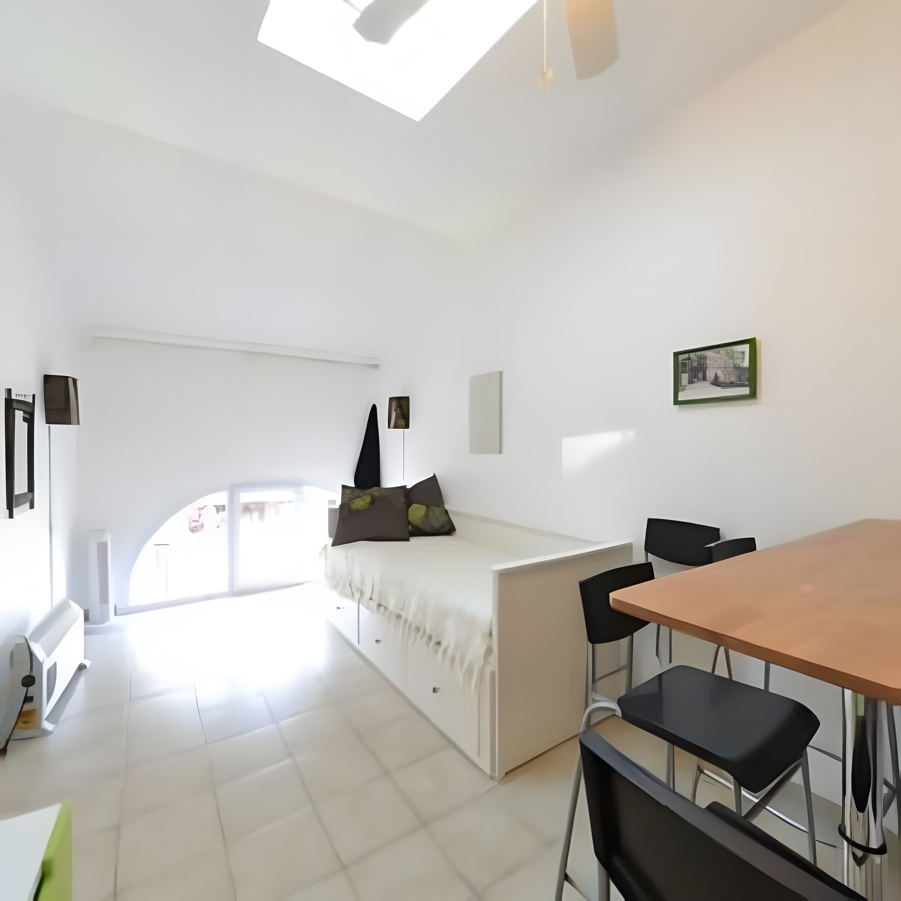 Une chambre moderne et minimaliste, comprenant un lit, une table à manger et des chaises.