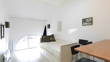Une chambre moderne et minimaliste, comprenant un lit, une table à manger et des chaises.