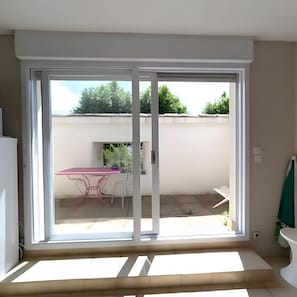Una habitación con puerta corrediza de vidrio que da a un patio exterior.