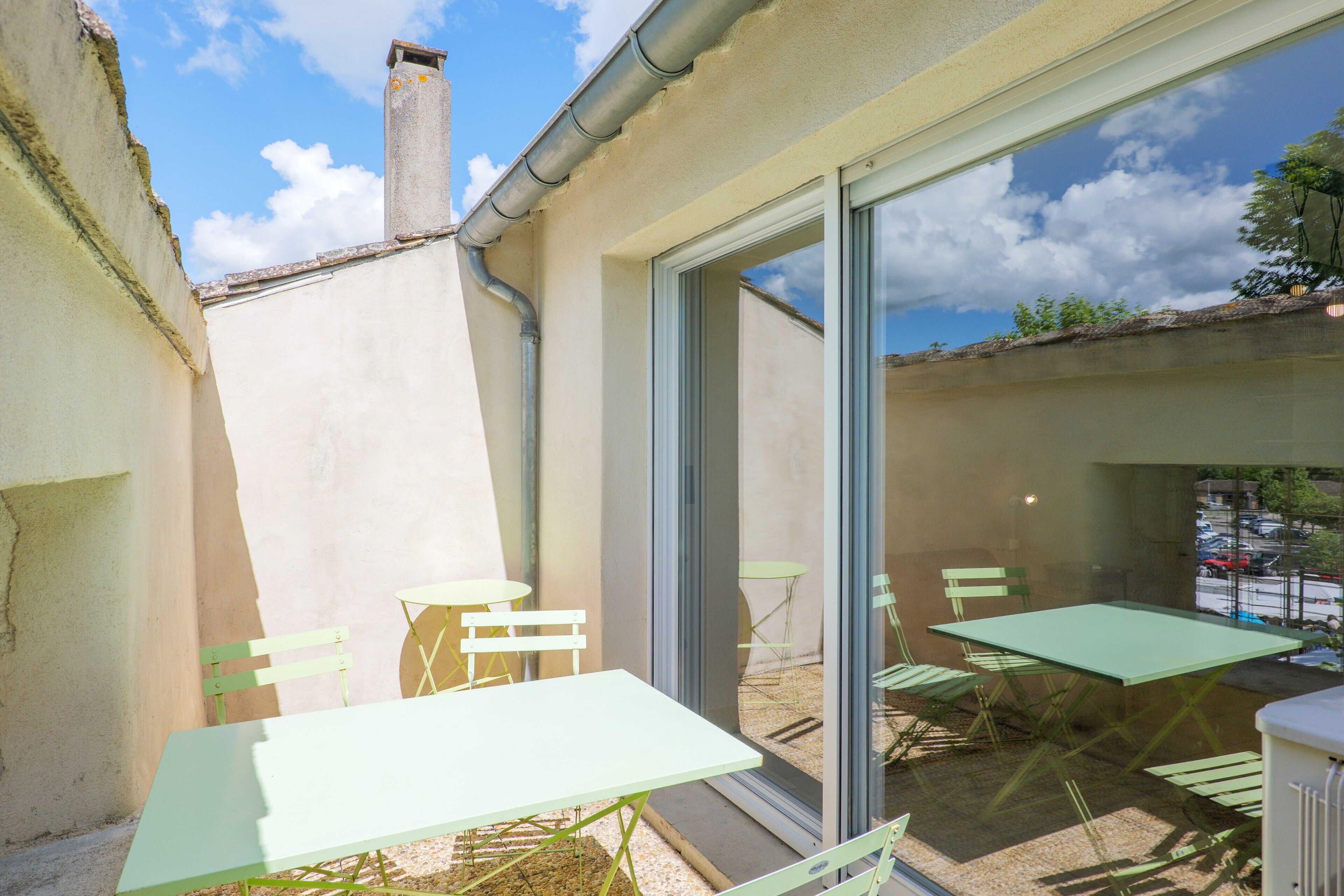 Een terras buiten met een tafel, stoelen, een schuifpui en uitzicht op de lucht.