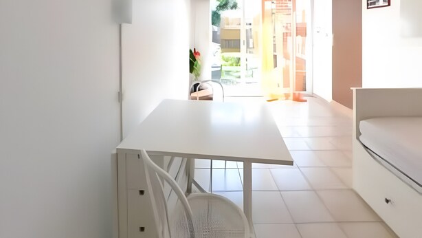 A modern, minimalist room with a white table, a white sofa, and a large window. - Gîte '03' with Wi-Fi (Vallon-Pont-d'Arc)