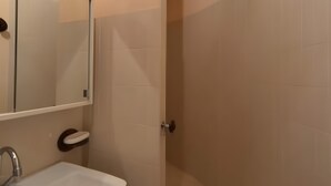 Un baño con lavamanos, espejo y zona de ducha.