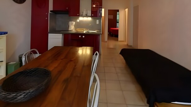 Una cocina moderna con armarios rojos, una mesa de comedor y una araña.