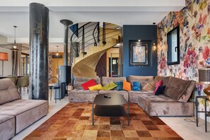 Un salon moderne comprenant un ensemble de canapés, une table basse et un escalier en colimaçon.
