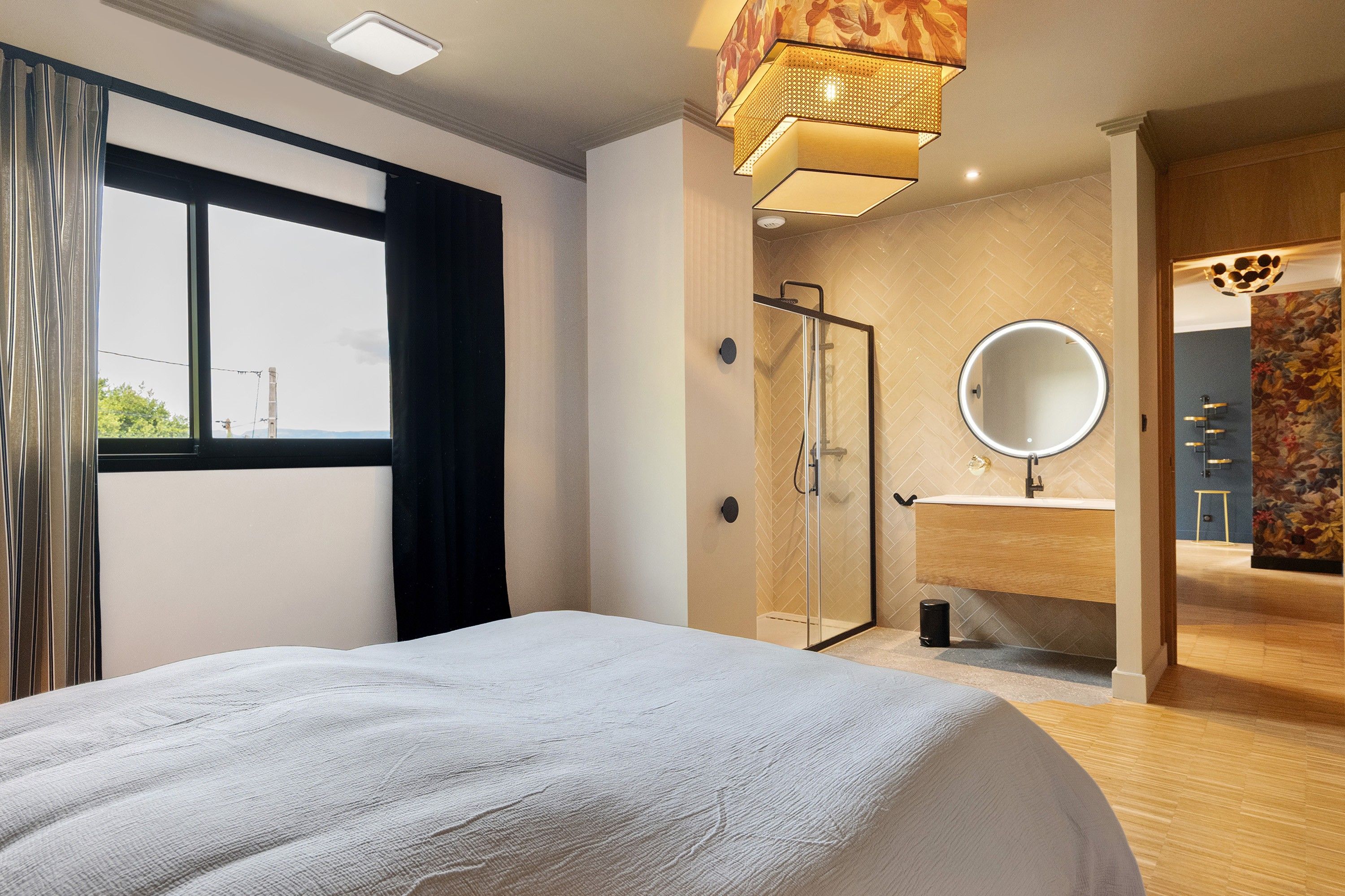 Ein modernes Schlafzimmer mit einem großen Bett, einem begehbaren Kleiderschrank, einem Badezimmer mit Dusche und Blick ins Freie.