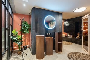 Een moderne badkamer met een zwarte marmeren wand, een ronde spiegel, twee wastafels en een houten vloer.