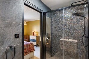 Een moderne badkamer met een douchecabine van glas en een zichtbaar slaapkamer met een bed en nachtkastje.