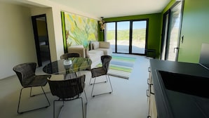 Ein modernes Wohnzimmer mit Essbereich, Sofa und großen Fenstern mit Blick ins Freie.