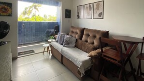 A living room with a sofa, a dining table, and a ceiling fan. - Giza's Corner - Near Sol Beach (João Pessoa)