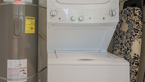 Une petite buanderie équipée d’un grand chauffe-eau, d’un lave-linge à chargement frontal et d’un étendoir à linge décoré.