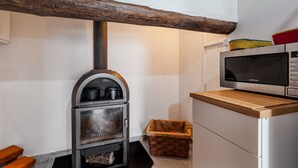 Eine Küche mit Holzofen, Mikrowelle und einer hölzernen Bank.
