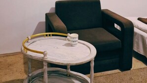 Ein Zimmer mit einem runden Holztisch mit weißer Tischplatte, einem schwarzen Sessel und einem gerahmten Kunstwerk an der Wand.