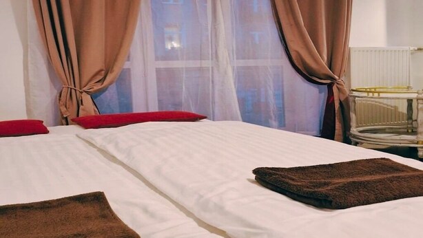 Ein Hotelzimmer mit einem Bett, braunen Vorhängen und einem Fenster mit Blick auf Gebäude.