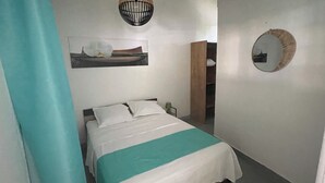Ein Schlafzimmer mit einem Bett, einem Gemälde, einem Spiegel und einer Tür zu einem Badezimmer.