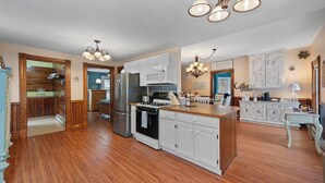 Una cocina amplia con piso de madera, muebles de cocina blancos, una isla central y un refrigerador.