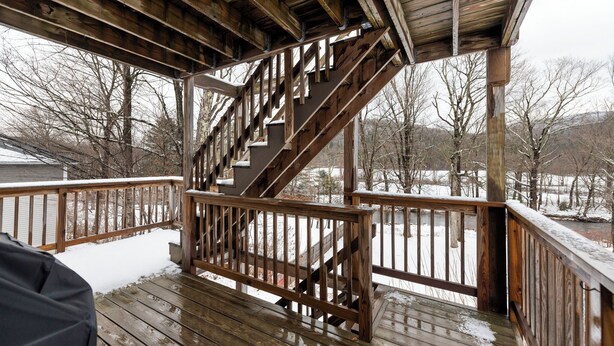 Una escalera de madera conduce a un porche cubierto con vistas a un paisaje nevado.