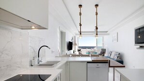 A modern kitchen with a built-in dishwasher, a large window, and a dining area with a view. - Delmar Holiday Home with Sea View, Wi-Fi, and Air Conditioning (Quarteira)