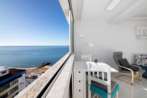 A balcony with a view of the sea, a white table with chairs, and a grey sofa. - Delmar Holiday Home with Sea View, Wi-Fi, and Air Conditioning (Quarteira)